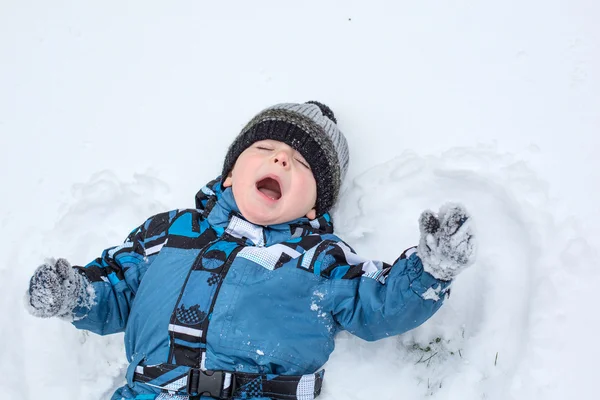Adorable toddler boy making angel on snow — Stock Photo, Image