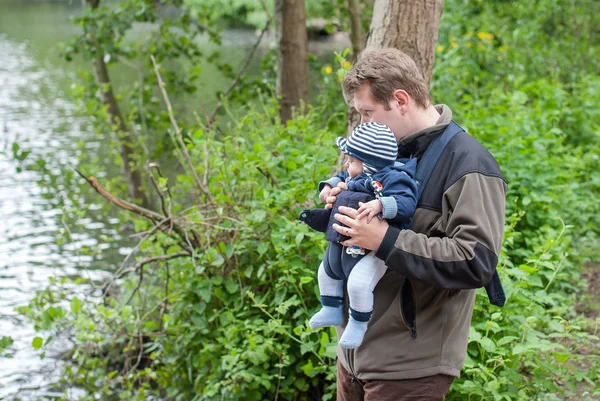 Young father carrying son in sling in park — Stock Photo, Image