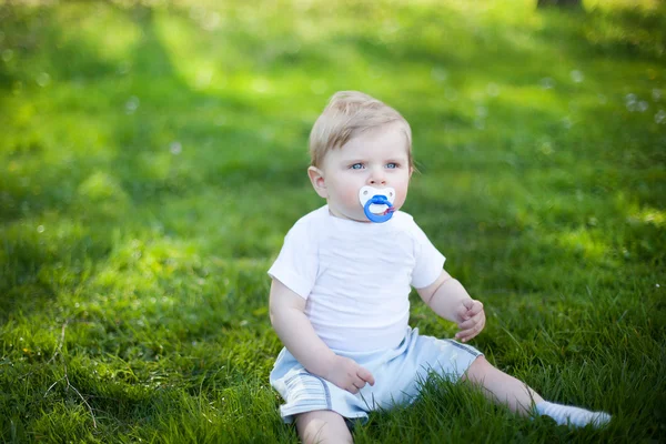 Rozkošný chlapeček na zelené trávě na jaře — Stock fotografie