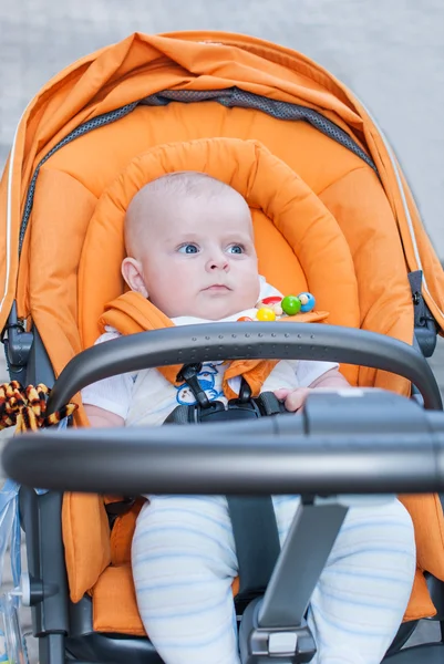 Lovely babyjongen buiten in oranje wandelwagen — Stockfoto