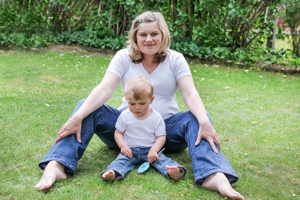 Young pregnant woman and little son in summer garden — Stock Photo, Image