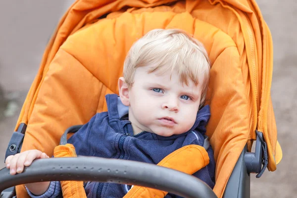 Krásné batole chlapec venkovní v oranžový kočárek — Stock fotografie