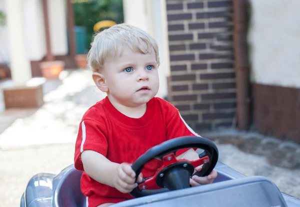 Pequeño todder chico jugando con Grande juguete coche — Foto de Stock