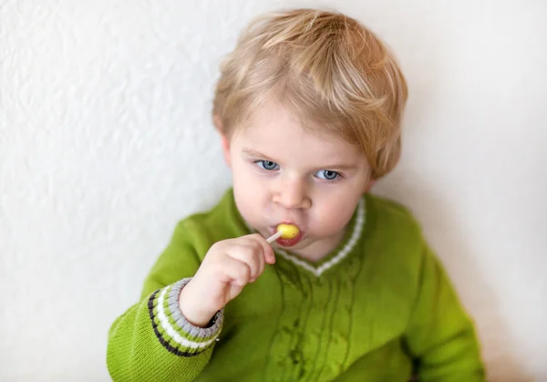 Little happy toddler boy eating lollipop — Stock Photo, Image