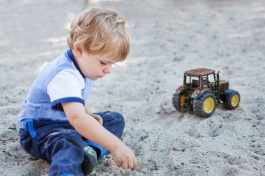 kum ve oyuncak oynarken küçük yürümeye başlayan çocuk