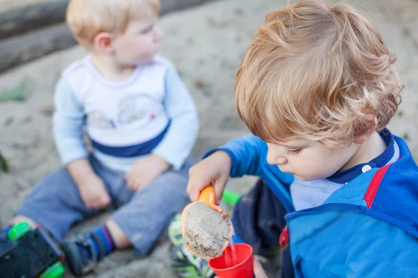 To små gutter som leker med sand om sommeren – stockfoto