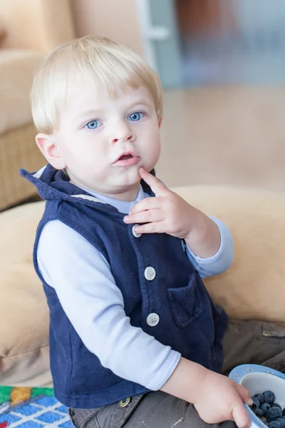 Menino pequeno comendo mirtilo em casa — Fotografia de Stock