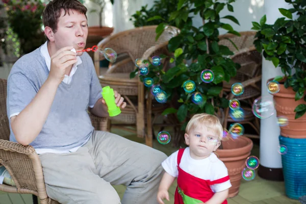 Genç Baba ve küçük çocuk yaz aylarında sabun köpüğü ile oynama — Stok fotoğraf