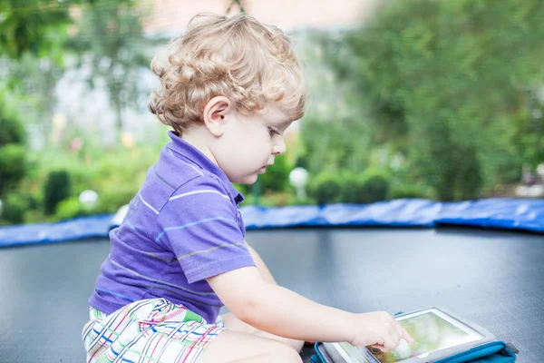 Маленький мальчик играет с планшетным компьютером на улице — стоковое фото
