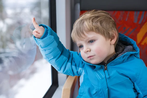 Schattige kleine jongen kijkt uit raam van de trein — Stockfoto