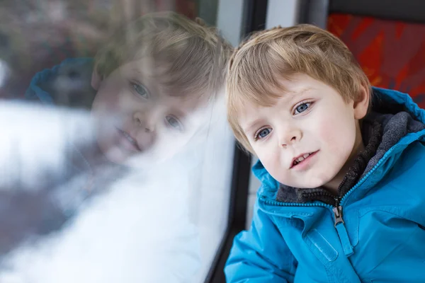 Mignon petit garçon regardant par la fenêtre du train — Photo