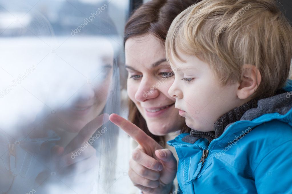 Mother and toddler son looking out train window outside