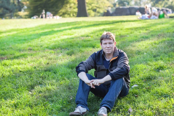 Hermoso hombre sentado en el parque de primavera —  Fotos de Stock