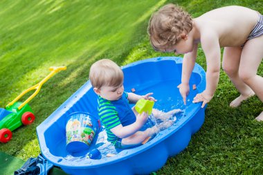 İki kardeş çocukları yaz aylarında su ile eğleniyor