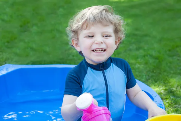 Little blond toddler boy playing with water in summer — Stock Photo, Image