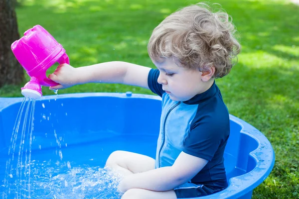 Menino loiro brincando com água no verão — Fotografia de Stock