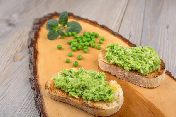 Delicioso crostini con puré de frijoles crudos y guisantes — Foto de Stock