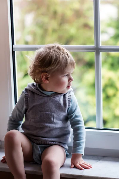 Schattig peuter jongen kijken uit het raam — Stockfoto