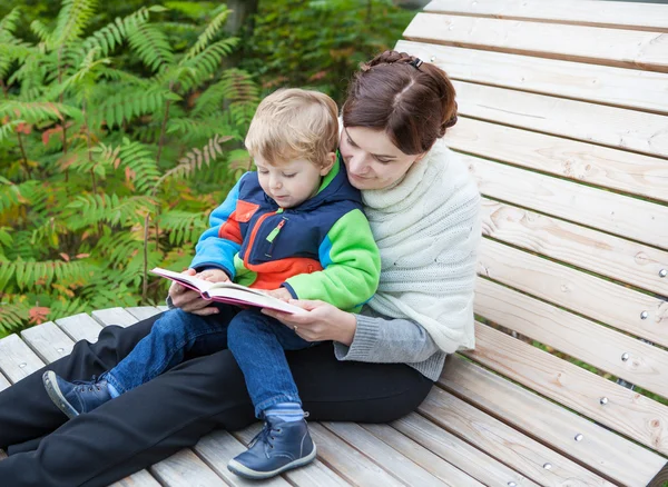 Junge Mutter und Kleinkind lesen Buch im Freien — Stockfoto