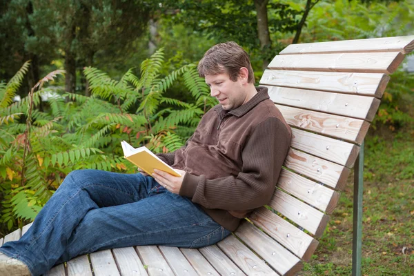 Portrait of young man reading book in forest — Stock Photo, Image