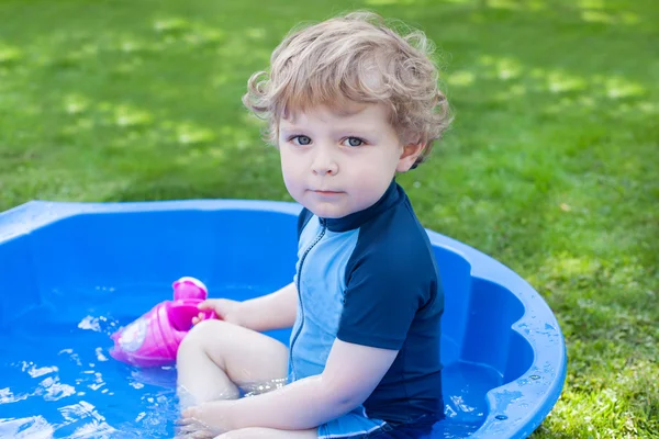 Little blond toddler boy playing with water in summer — Stock Photo, Image