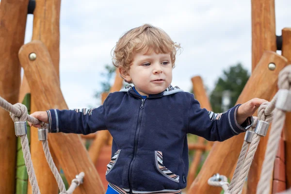 Petit garçon tout-petit assis sur l'aire de jeux — Photo