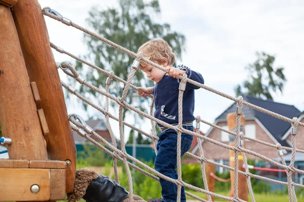 Petit garçon tout-petit assis sur l'aire de jeux — Photo