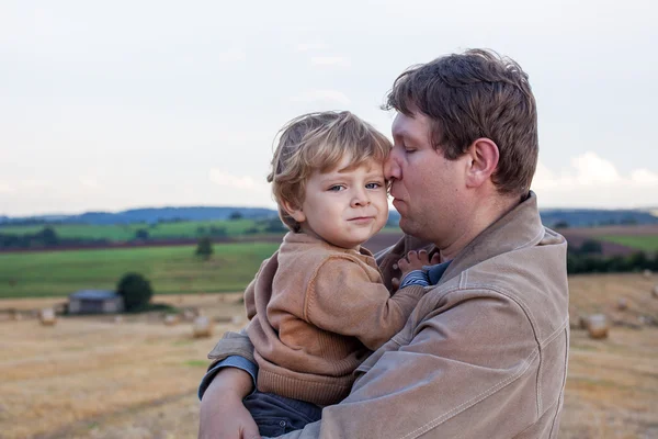 Young father and adorable little son hugging on straw field — Stock Photo, Image