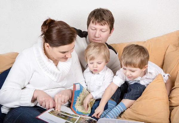 Gelukkige familie van een vier kijken naar oude foto's thuis. — Stockfoto