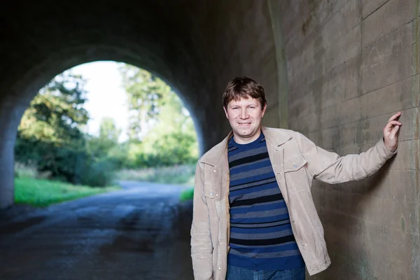 Young man posing in tunnel on sunny day — Stock Photo, Image