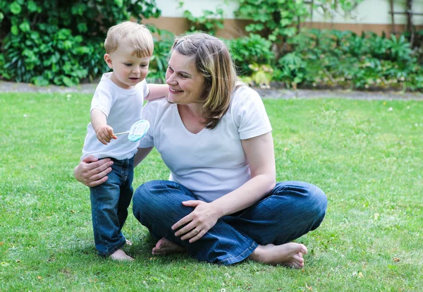 Mujer embarazada y pequeño hijo en el jardín de verano — Foto de Stock