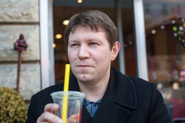 Young man drinking juice in city cafe — Stock Photo, Image