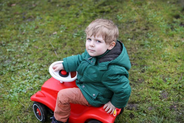 Little todder boy playing with big toy car — Stock Photo, Image