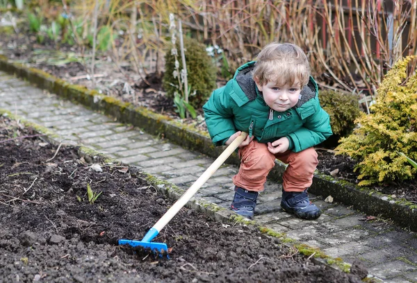 Little boy in spring with garden hoe — Stock Photo, Image