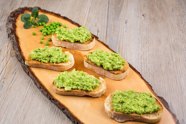 Crostini delicioso com purê de feijão cru e ervilhas — Fotografia de Stock