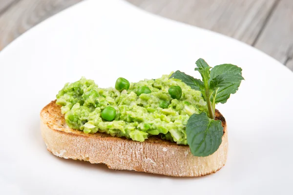 Delicioso crostini con puré de frijoles crudos y guisantes — Foto de Stock