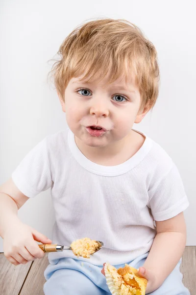 Little boy eating cheesecake muffin. — Stock Photo, Image