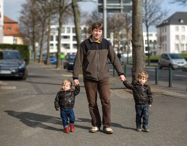 Young man and two little boys walking through spring city — Stock Photo, Image