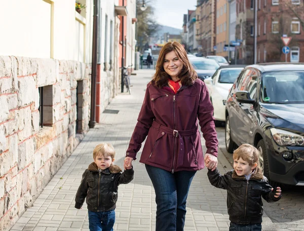 Young woman and two little boys walking through spring city — Stock Photo, Image