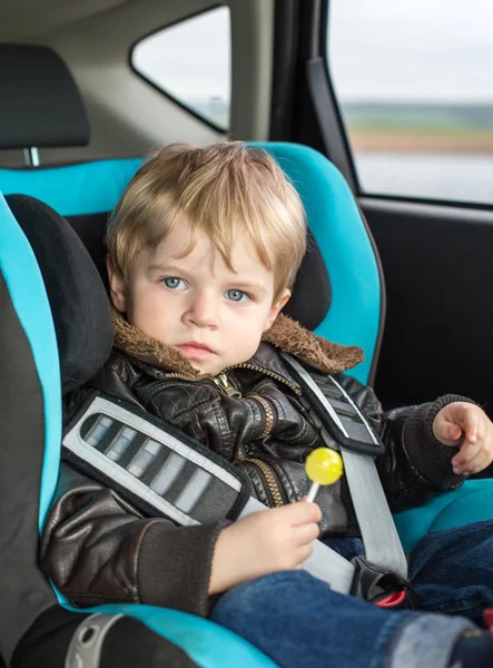 Peuter in veiligheid autostoel eten snoep — Stockfoto