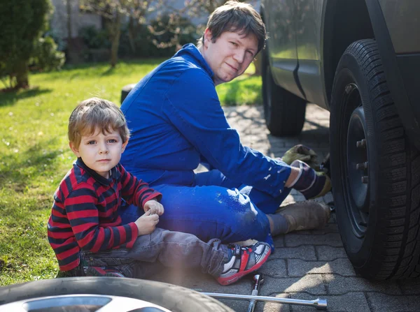 Liten pojke och hans pappa byta hjul på bilen — Stockfoto