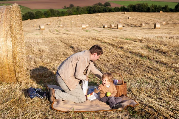 Jovem e menino fazendo piquenique no campo de feno — Fotografia de Stock