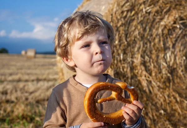ドイツ語プレッツェル goden 干し草フィールドに食べる小さな男の子 — ストック写真