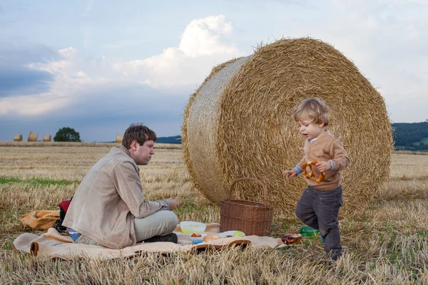 Young man and little boy making picnic on hay field — Stock Photo, Image
