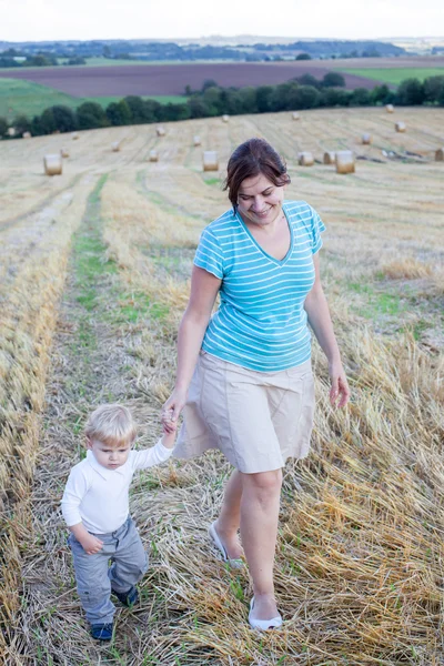 Ung mamma och hennes lille son ha kul i halm fältet — Stockfoto