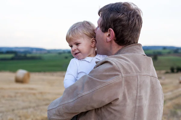 Giovane padre e adorabile piccolo figlio che si abbraccia sul campo di paglia — Foto Stock