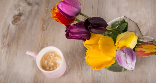 Tulipas coloridas e uma xícara de café fresco — Fotografia de Stock