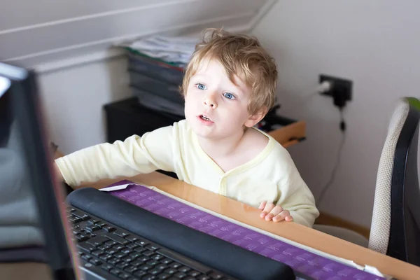 Маленький мальчик учится на компьютере дома — стоковое фото