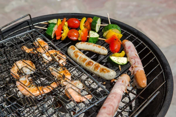 Korv, jätteräkor och grönsaker spett rökning på grillen — Stockfoto