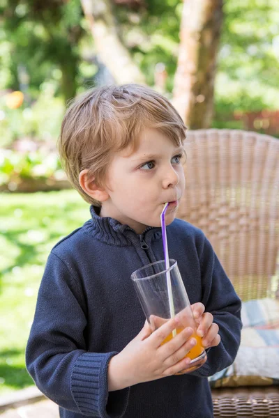 Happy little boy drinking orange juice with straw — Stock Photo, Image